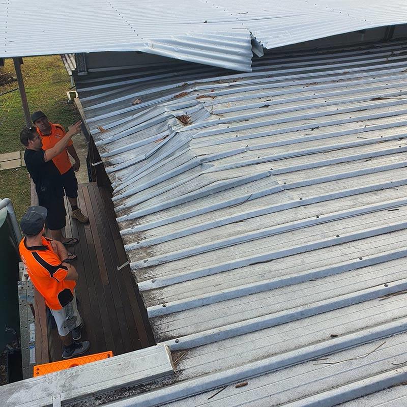 The Roofing Group team inspecting and assessing a storm damaged metal roof